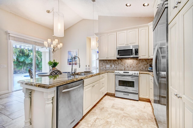 kitchen with a peninsula, a sink, lofted ceiling, stone countertops, and appliances with stainless steel finishes
