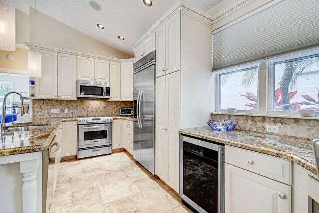 17586 Tiffany Trace Dr, Boca Raton, FL 33487 - kitchen featuring beverage cooler, appliances with stainless steel finishes, a sink, light stone counters, and vaulted ceiling