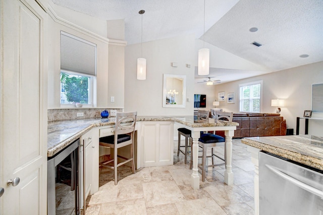 kitchen featuring lofted ceiling, wine cooler, visible vents, hanging light fixtures, and a textured ceiling