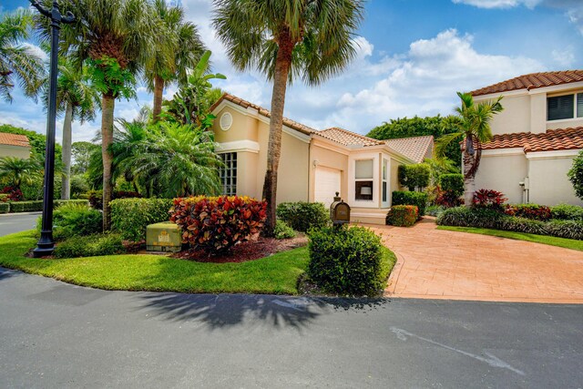 17586 Tiffany Trace Dr, Boca Raton, FL 33487 - mediterranean / spanish-style house with an attached garage, a tiled roof, stucco siding, and decorative driveway