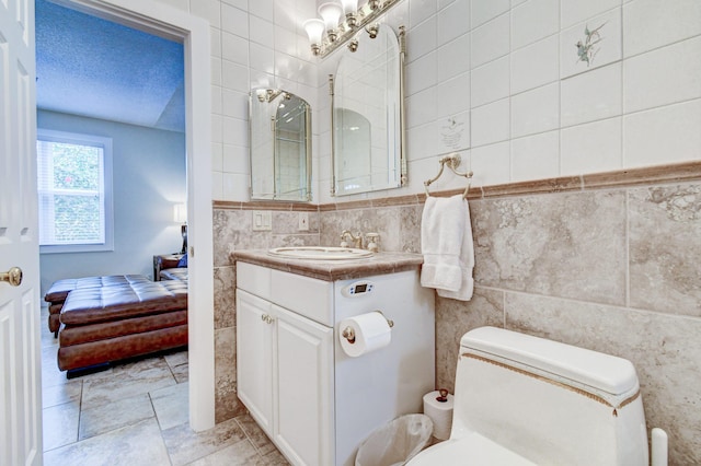bathroom with tile walls, toilet, vanity, and connected bathroom