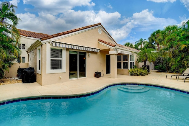 back of house with stucco siding, a tile roof, an outdoor pool, and a patio