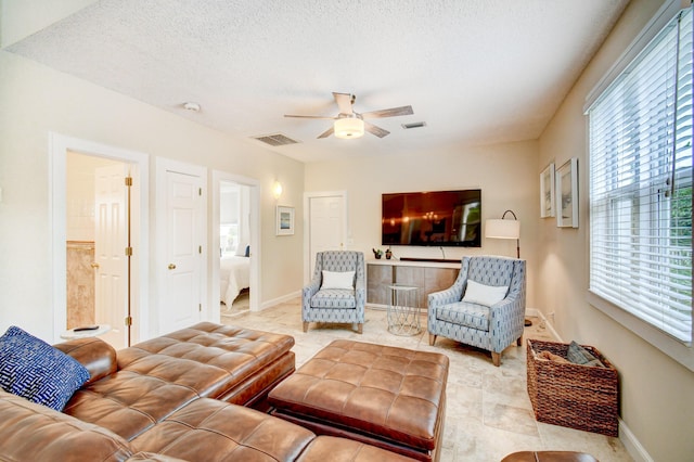 living area featuring visible vents, a ceiling fan, and a healthy amount of sunlight