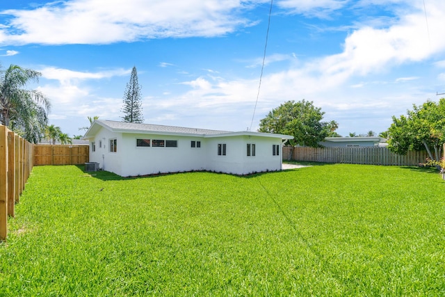 2771 NE 53rd St, Lighthouse Point, FL 33064 - back of house with a fenced backyard, central AC unit, stucco siding, and a lawn