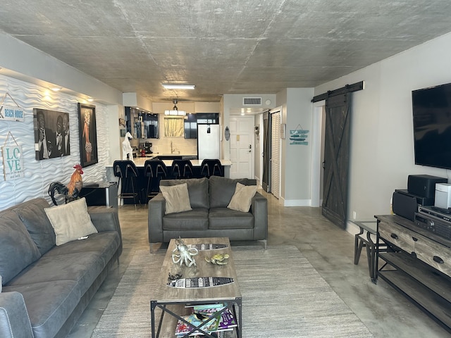 3570 S Ocean Blvd Unit 205, South Palm Beach, FL 33480 - living room featuring a barn door, visible vents, and concrete flooring