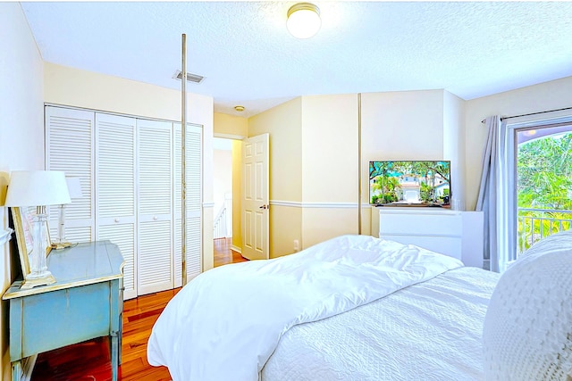 bedroom featuring wood finished floors, visible vents, and a textured ceiling