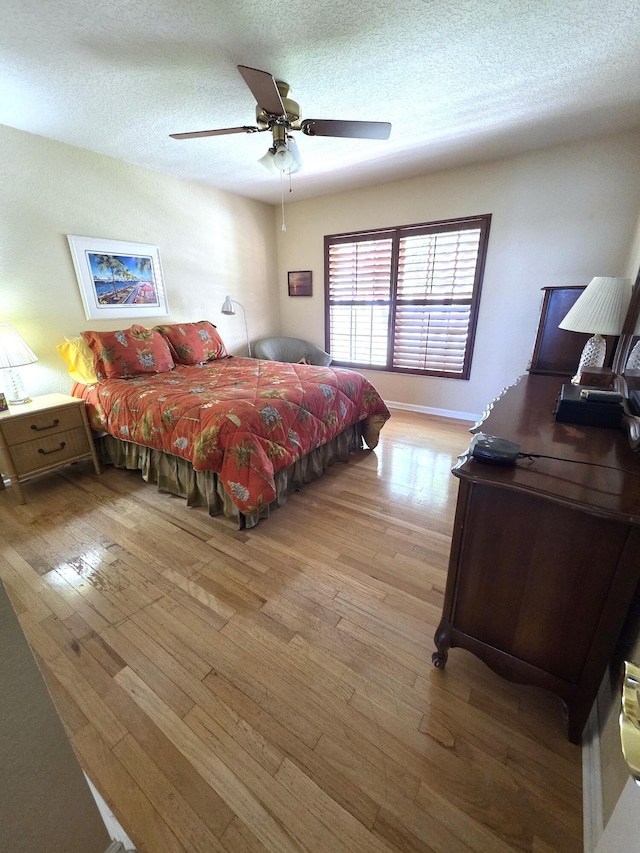 bedroom featuring hardwood / wood-style flooring, a textured ceiling, and a ceiling fan