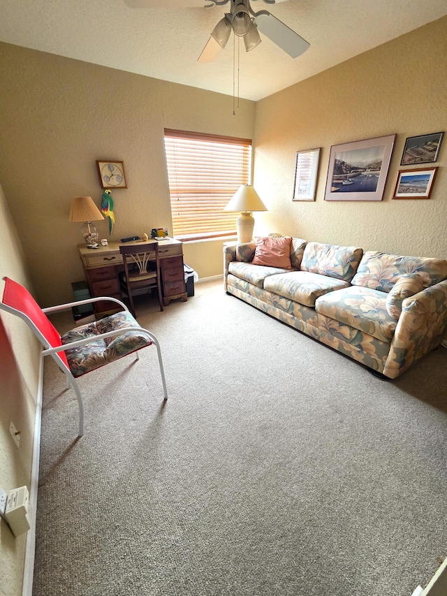 carpeted living area with a textured wall and ceiling fan