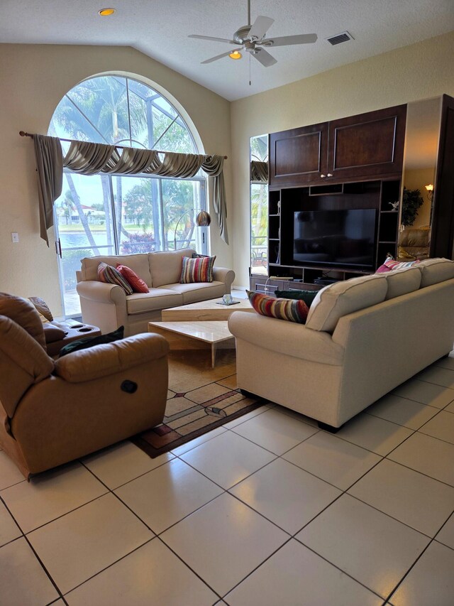 living area with ceiling fan, vaulted ceiling, visible vents, and light tile patterned floors