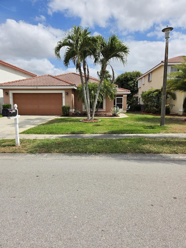 view of front of house featuring a front lawn, stucco siding, a tile roof, driveway, and a garage