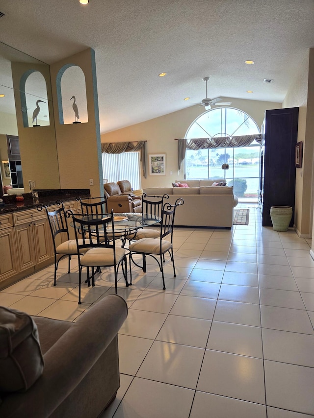 dining area featuring lofted ceiling, a textured ceiling, ceiling fan, and light tile patterned flooring
