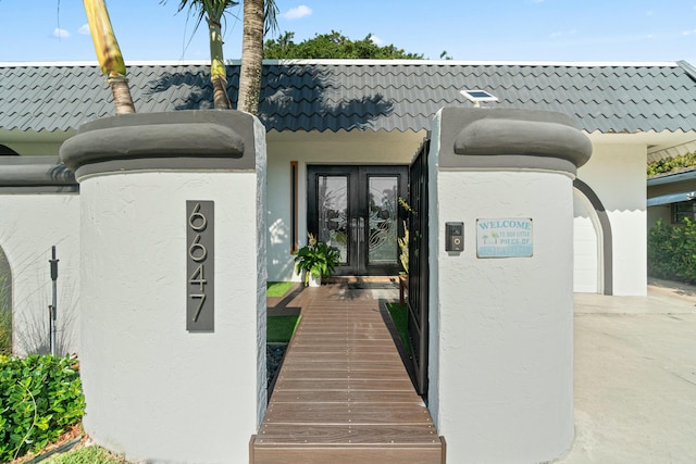 property entrance with a tiled roof, french doors, and stucco siding