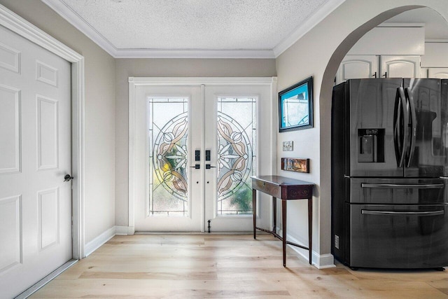 entrance foyer featuring baseboards, light wood-style flooring, french doors, and arched walkways