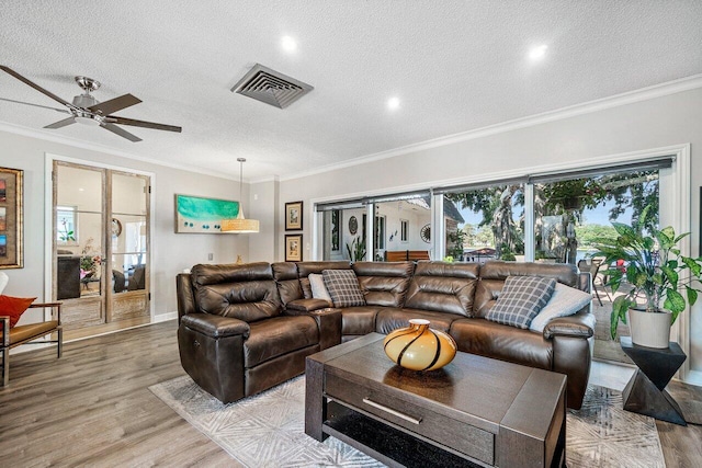 living area with wood finished floors, visible vents, and a textured ceiling