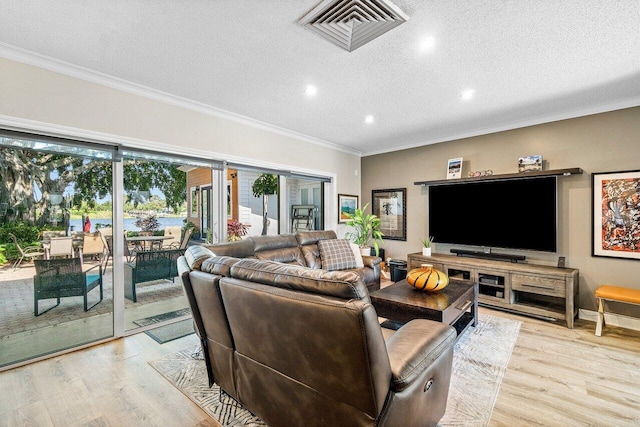 living area featuring recessed lighting, light wood finished floors, visible vents, ornamental molding, and a textured ceiling