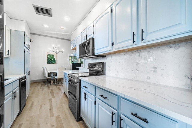 kitchen with light wood finished floors, backsplash, visible vents, black appliances, and a chandelier