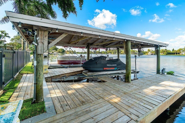 view of dock featuring a water view, boat lift, and fence