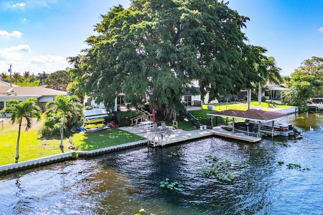 view of dock with boat lift, a water view, and a yard