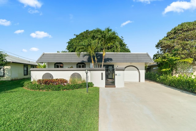view of front of property with a tiled roof, driveway, a front yard, and a garage