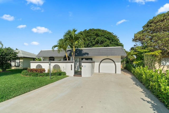 view of front facade featuring a tiled roof, concrete driveway, an attached garage, a front yard, and stucco siding