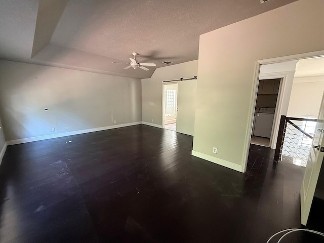 spare room with a ceiling fan, a barn door, washer / dryer, a textured ceiling, and baseboards