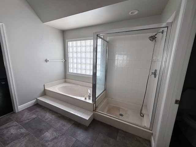 full bath featuring a shower stall, a garden tub, and baseboards