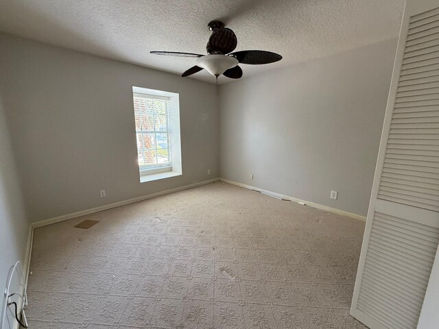 carpeted empty room with ceiling fan, a textured ceiling, and baseboards