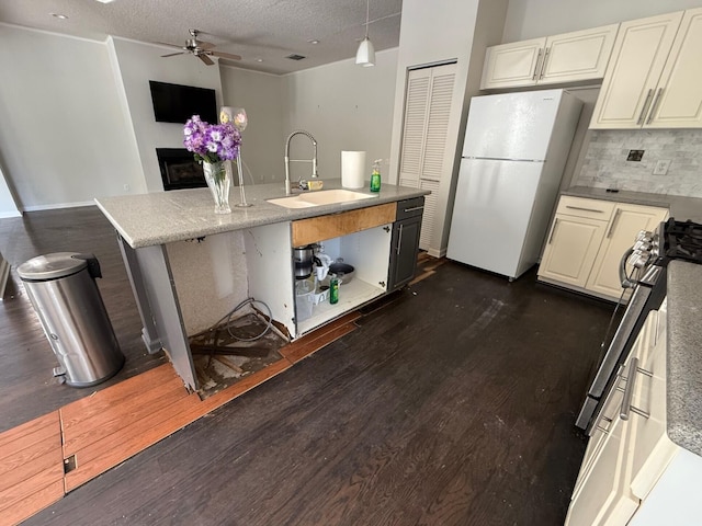 kitchen with a sink, freestanding refrigerator, stove, a ceiling fan, and backsplash