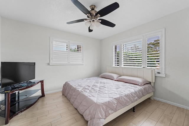 bedroom with wood finished floors, a ceiling fan, baseboards, and multiple windows