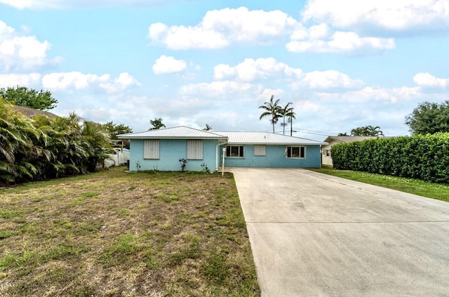 ranch-style home featuring stucco siding, metal roof, a front yard, and concrete driveway