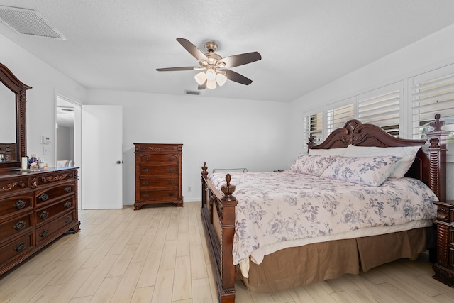 bedroom featuring light wood-style floors, visible vents, and a ceiling fan