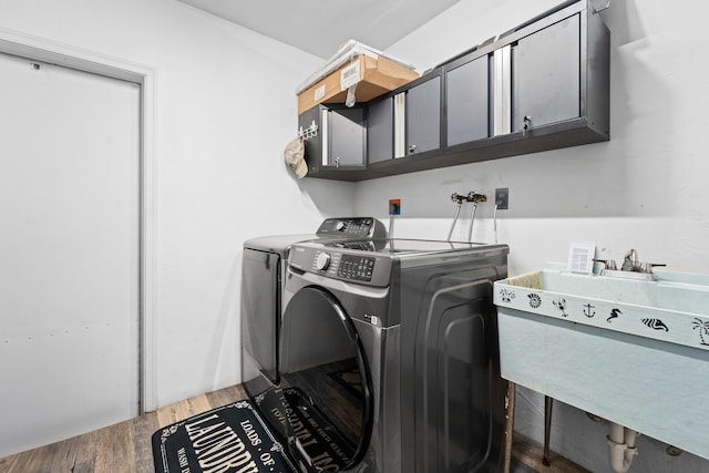 laundry room featuring washing machine and dryer, cabinet space, and wood finished floors