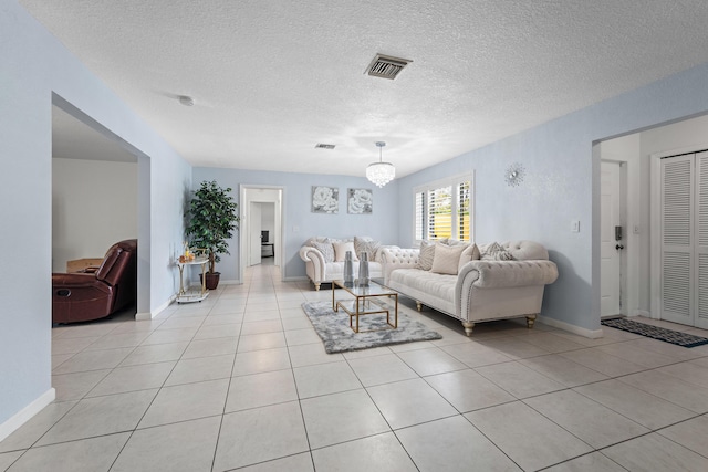 living area featuring baseboards, a textured ceiling, visible vents, and light tile patterned floors