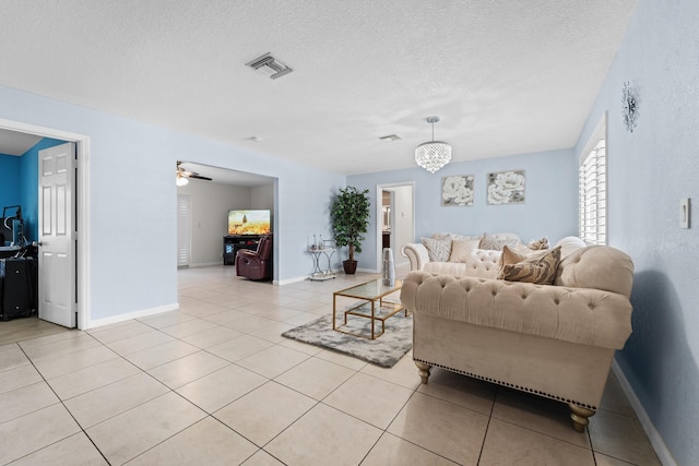 living room featuring visible vents, a ceiling fan, light tile patterned floors, baseboards, and a textured ceiling