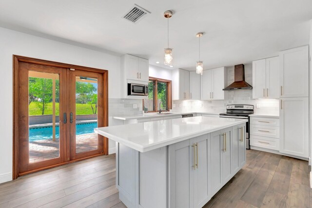 4770 Fox Hunt Trl, Boca Raton, FL 33487 - kitchen with appliances with stainless steel finishes, wall chimney exhaust hood, a sink, backsplash, and wood finished floors