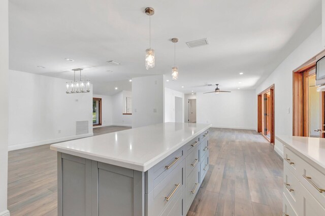 4770 Fox Hunt Trl, Boca Raton, FL 33487 - kitchen with washer and clothes dryer, gray cabinetry, light wood-type flooring, light countertops, and a kitchen island