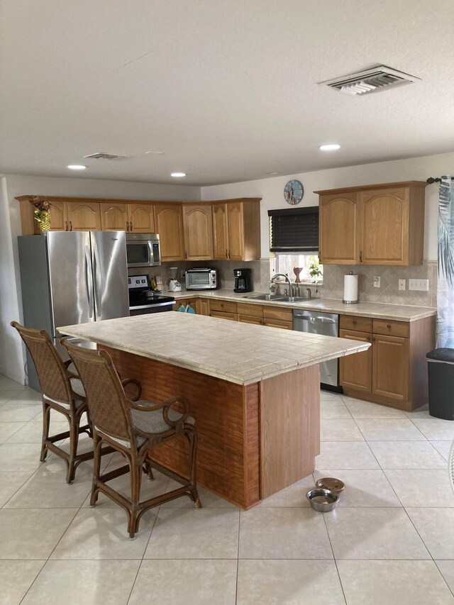 1672 Thumb Point Dr, Fort Pierce, FL 34949 - kitchen with a breakfast bar, visible vents, a kitchen island, tasteful backsplash, and appliances with stainless steel finishes