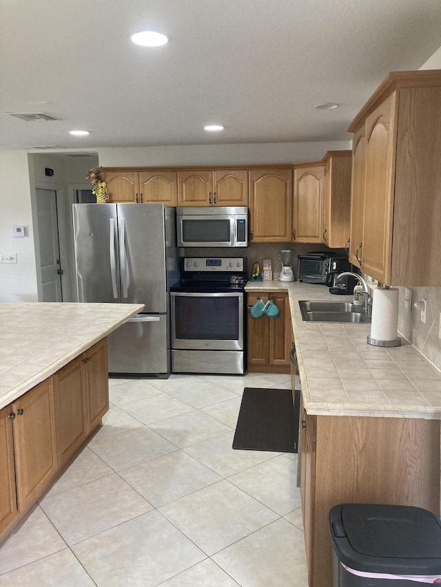 1672 Thumb Point Dr, Fort Pierce, FL 34949 - kitchen featuring tile counters, brown cabinets, recessed lighting, stainless steel appliances, and a sink