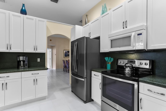23437 Torre Cir, Boca Raton, FL 33433 - kitchen with electric stove, white microwave, arched walkways, freestanding refrigerator, and dark countertops