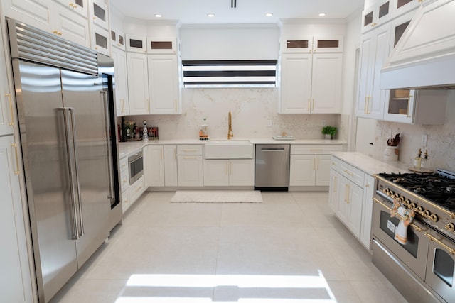 2810 F Rd, Loxahatchee Groves, FL 33470 - kitchen with premium appliances, premium range hood, backsplash, light countertops, and white cabinetry