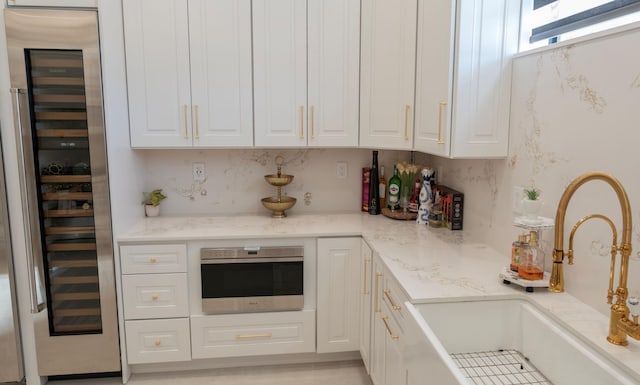 2810 F Rd, Loxahatchee Groves, FL 33470 - kitchen with beverage cooler, white cabinetry, light stone counters, and wall oven
