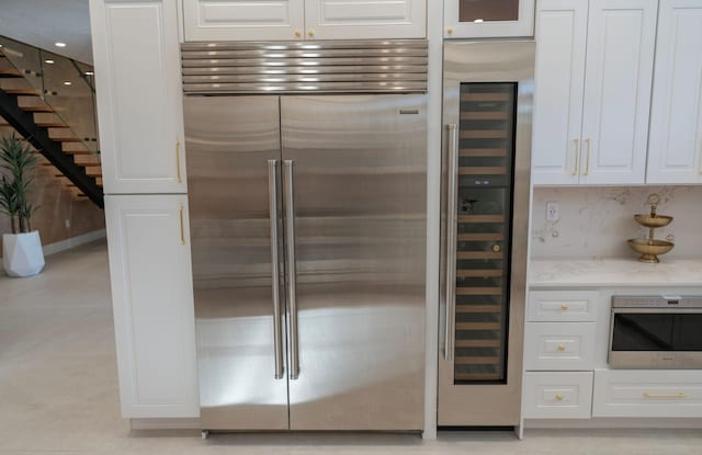 2810 F Rd, Loxahatchee Groves, FL 33470 - kitchen with built in refrigerator, white cabinets, light stone countertops, and wine cooler