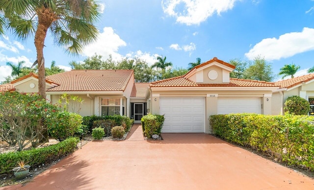 mediterranean / spanish-style home with stucco siding, an attached garage, driveway, and a tiled roof