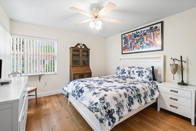 bedroom with baseboards, a ceiling fan, a textured ceiling, and wood finished floors