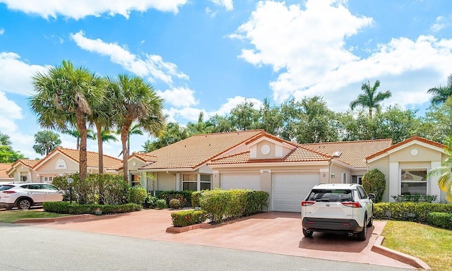 mediterranean / spanish house featuring concrete driveway, a tiled roof, an attached garage, and stucco siding