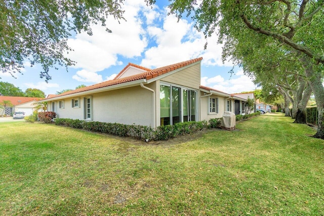 view of property exterior featuring a tiled roof, stucco siding, and a yard