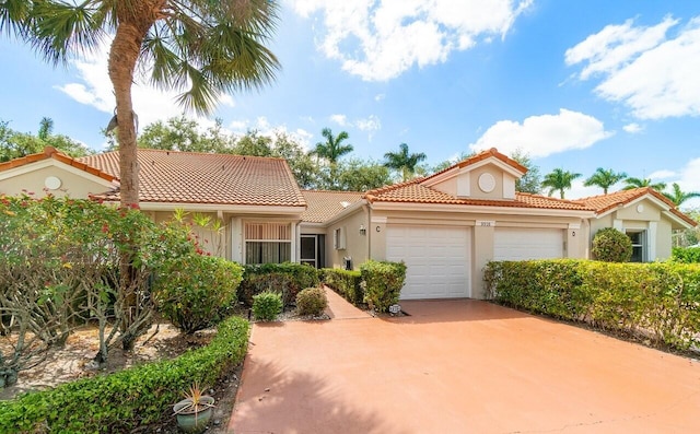 mediterranean / spanish home with a tiled roof, an attached garage, driveway, and stucco siding
