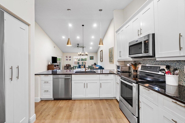 kitchen with appliances with stainless steel finishes, a sink, a peninsula, light wood-style floors, and white cabinetry