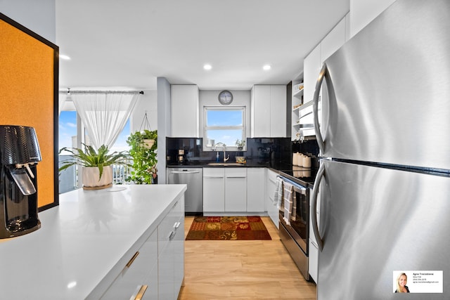 137 Golden Isles Dr Unit 1605, Hallandale Beach, FL 33009 - kitchen featuring appliances with stainless steel finishes, white cabinets, recessed lighting, light wood-style flooring, and tasteful backsplash