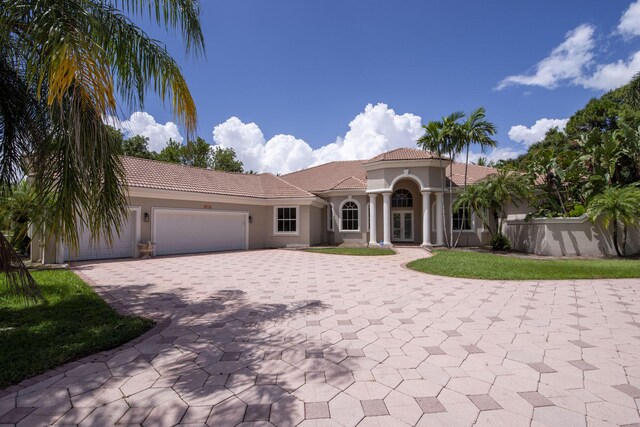 8280 Woodsmuir Dr, Palm Beach Gardens, FL 33412 - mediterranean / spanish home with a tiled roof, decorative driveway, stucco siding, an attached garage, and french doors